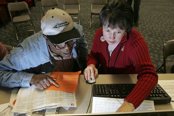 A volunteer uses a computer to help a senior during a Medicare enrollment event.