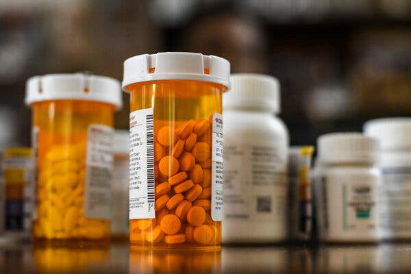 Several containers of prescription medications stand on a glossy surface.