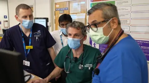 Dr Raj Paw (in light blue) and colleagues look at computer statistics assessing the hospital's capacity