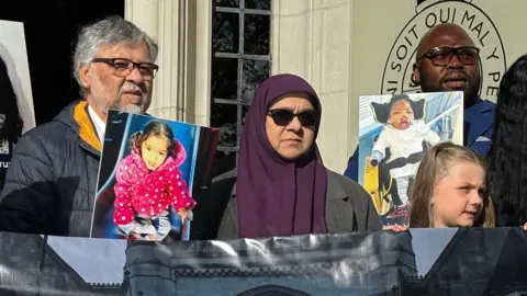 BBC  Rashid and Aliya Abbasi (left), the parents of Zainab Abbasi, Lanre Haastrup (L), father of Isaiah Haastrup; outside the Supreme Court in London. They are holding up pictures of their children.