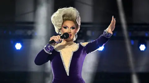Getty Images Drag Queen The Vivienne singing in a purple jumpsuit on stage at the opening of the Eurovision Song Contest 2023 in Liverpool
