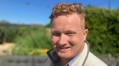 A man with strawberry blond hair smiles at the camera