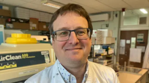 A man in glasses and a white lab coat