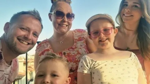 Nye family A family holiday photo including one man, one woman, two girls and a young boy. All of them are smiling. 