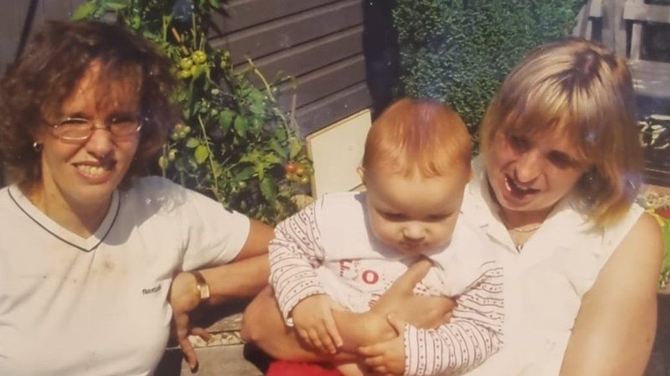 Two women, one of whom is holding a baby, old photo