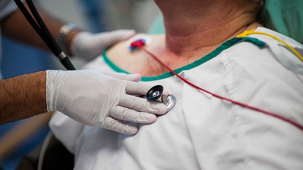 A doctor listening to a patient's heartbeat with a stethoscope