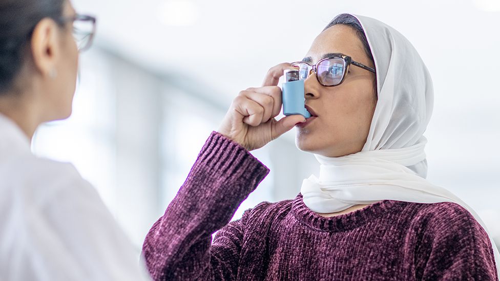 A woman using an asthma inhaler