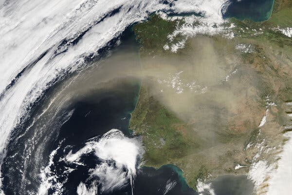 A wispy brown dust plume, seen from high in space, extends over Portugal and Spain. 