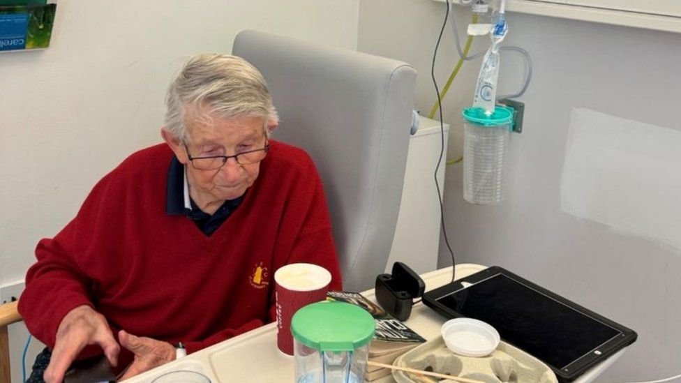 Alexander Red sitting in a grey hospital chair