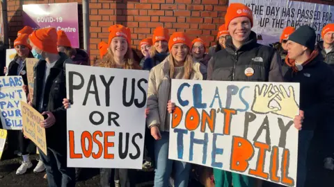 PA Images Junior doctors on the picket line at the RVH holding up posts saying 'claps don't pay the bills'