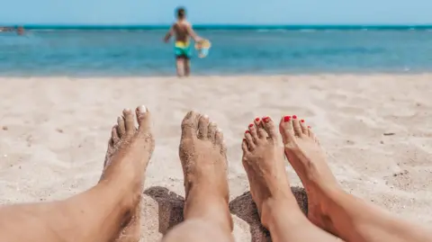 Getty Images People lying on a beach in the sun