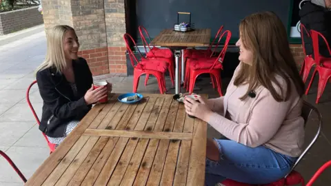 Alex Dunlop/BBC Gemma Cutler sitting in a cafe with Jen Moore