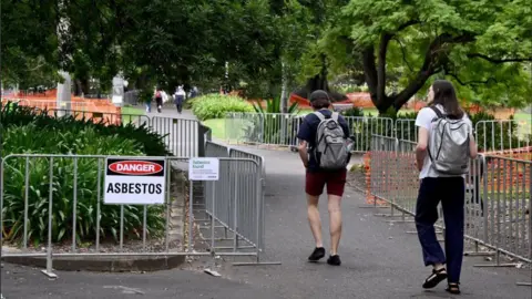 Shutterstock People walking by an asbestos sign