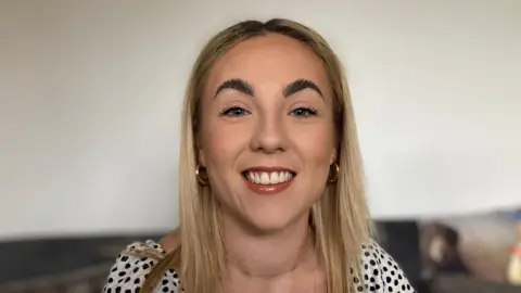 Alex Dunlop/BBC Gemma Cutler smiling at the camera in a black and white blouse