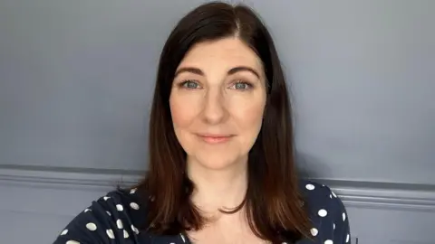 PHA Louise Flanagan from the PHA looking directly at the camera, smiling and wearing a navy tshirt with white polka dots