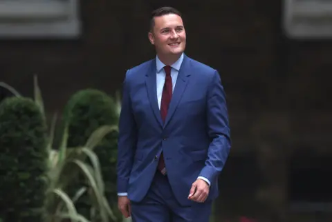 EPA  Wes Streeting smiling as he walks down a street.