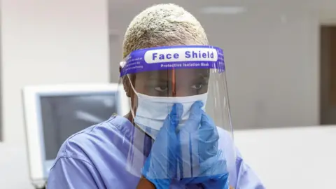 Getty Images Healthcare worker wearing a surgical mask and face shield during the pandemic.