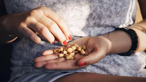 Getty Images Woman eating a pile of peanuts from her hands