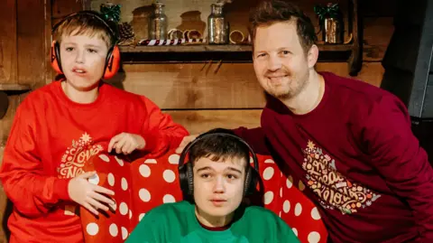 John Thompson Jude (middle) wears a green jumper, Tommy (left) wears a red jumper and James (right) wears a maroon jumper, all Christmas themed