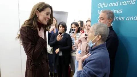 PA Media The Princess of Wales puts her hand to her chest as she speaks to a woman with a face mask over her chin at the Royal Marsden