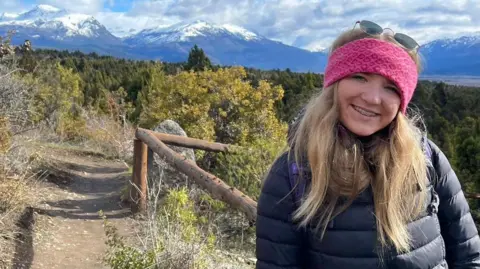 Fflur James Student Fflur James smiles at the camera and she is wearing a pink headband, with sunglasses on her head. She is in a countryside location with snow-topped mountains in the background