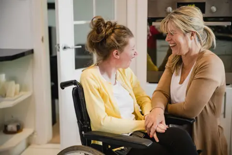 Getty Images A stock image of a disabled woman and a carer.