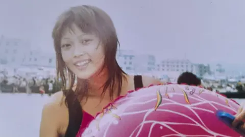 Family handout A teenage girl with shoulder-length hair, dressed in a swimsuit, stands behind a rubber ring, with a beach behind her