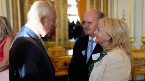 PA Media King Charles III speaks with Alistair and Heather James, the parents of the late broadcaster Deborah James, during a reception in Buckingham Palace, London