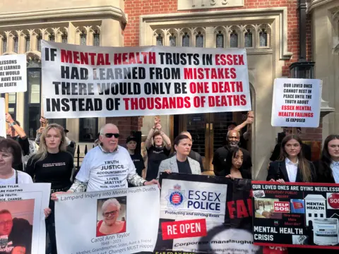 RICHARD DANIEL/BBC Family members stand outside Arundel House in London protesting. They are holding up banners. One reads: 'Our loved ones cannot rest in peace until the truth about Essex mental health failings are exposed'.