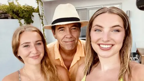 Jonathan Anstee A man in a fedora and two women smile for a selfie