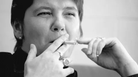Andrew Firth A black and white photo of Baroness Claire Fox of Buckley smoking a cigarette in a London cafe back in 2007