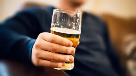 Getty Images A man's hand holding a pint glass filled with beer