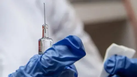 Getty Images A needle in the hands of a medic, with blue gloves in shot.