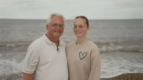 Jimmy Catchpole, with his daughter Mary, standing on a beach near their home in Norfolk.