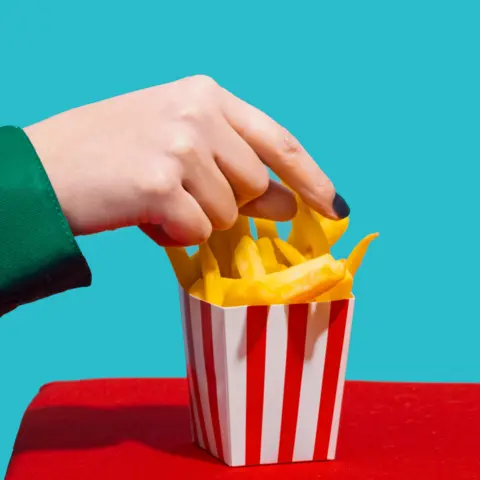 Getty Images Hand picking French fries from a box