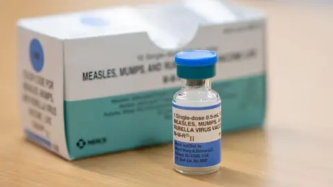 Getty Images A photograph of a measles vaccine in a glass vial with blue label