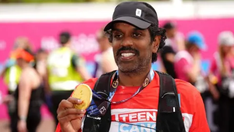 PA Media A picture of Romesh Ranganathan holding up his medal at the London Marathon finish line
