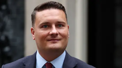 EPA Health Secretary Wes Streeting stands outside 10 Downing Street, wearing a blue shirt and a navy suit 