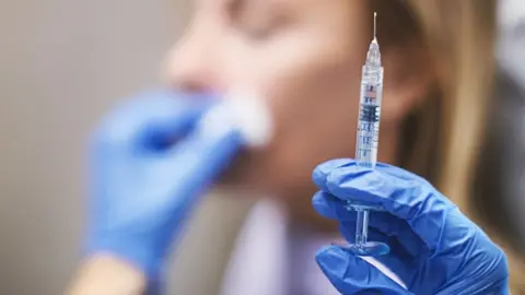 Getty Images Picture of a medical needle with a woman's face in the background