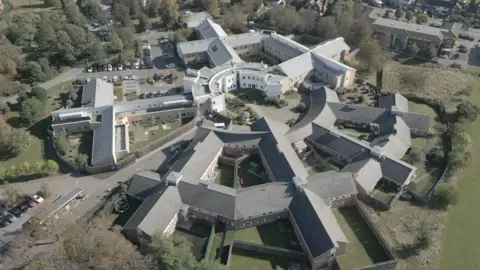 An aerial view of Goodmayes Hospital, Ilford. Several grey and white buildings forming a circle shape