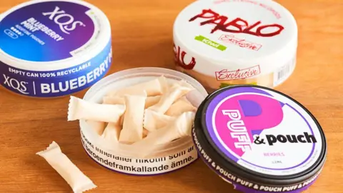 Getty Images An assortment of nicotine pouch cans, with one opened showing the pouches inside the case.