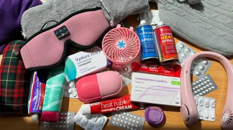 Kayleigh Webster Picture of Kayleigh Webster's migraine tool kit - medication boxes, eye mask, deep heat, headphones, a fan and hot water bottles