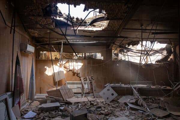 A destroyed building with holes in the ceiling and wall and rubble inside.