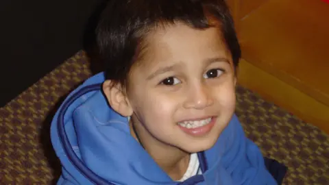 Amrit Paul A young Amrit at 4-years-old. He's sat looking up and smiling at the camera wearing a blue jumper.