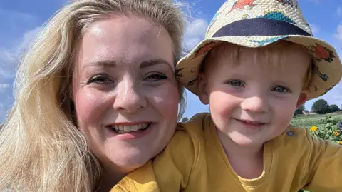 Family photo Kristal and her son Austin smiling at the camera. Austin is wearing a yellow top and sunhat
