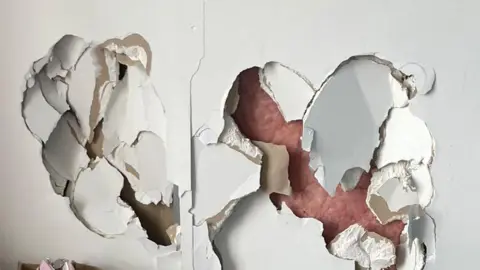 A view of a damaged wall with bags to the side