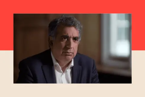 Panorama A still photograph of Mark McDonald wearing a suit and looking serious