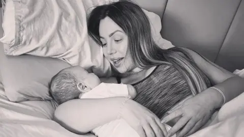 Holly Hagan-Blyth Black and white photo of Holly and her baby cuddling while lying in bed