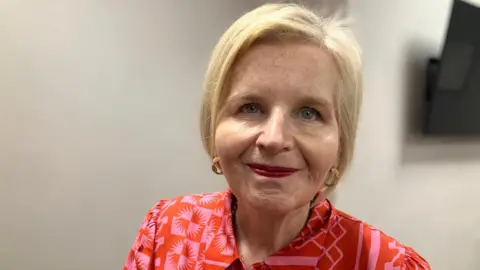 BBC Image of Donna. She has blonde hair and is wearing pink/red dress.