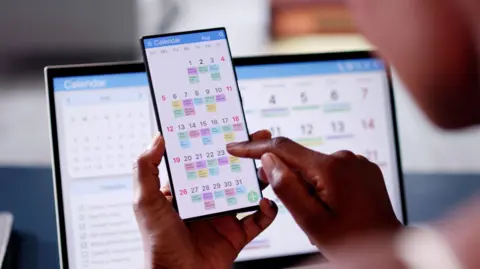 Getty Images Person looking at a phone calendar which is very busy 